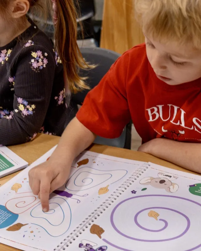 A child working through an activity book at a table