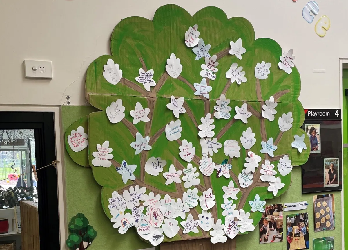 A painted gratitude tree on a service wall, its leaves covered in handwritten thank-yous
