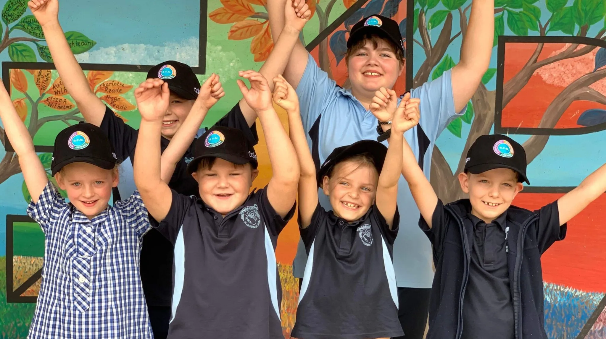 Primary school students smiling and raising their hands in a Resilience Project wellbeing lesson