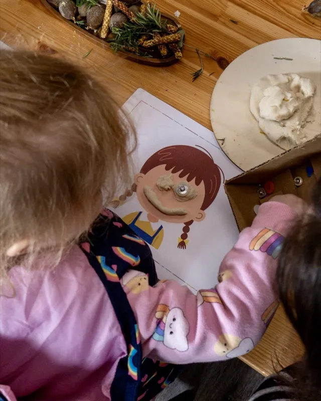 A child making a face on a paper plate at a craft table